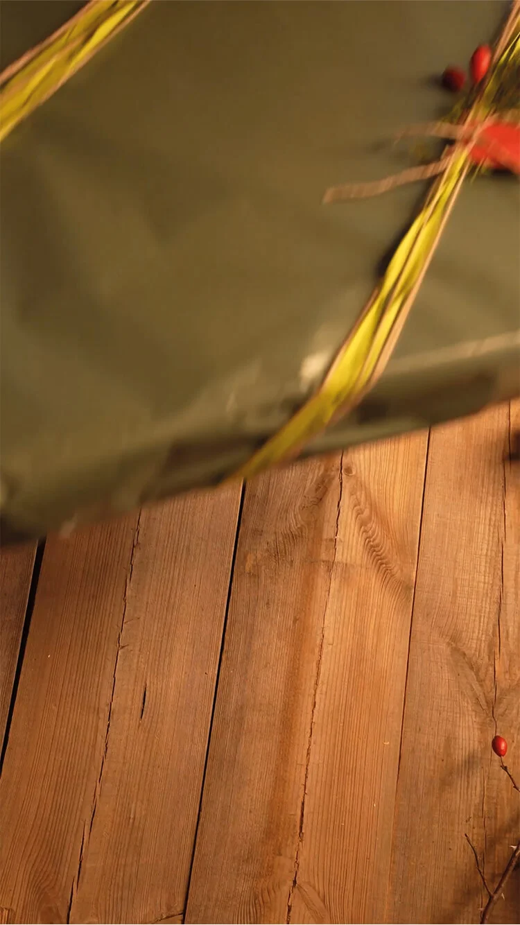 Handen die linten strikken en decoraties bevestigen op kerstcadeaus in natuurlijke kleuren. 