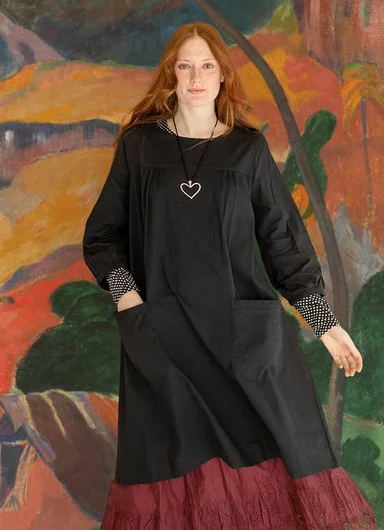 A woman wearing a brown blouse over a striped dress from Gudrun Sjödén. 