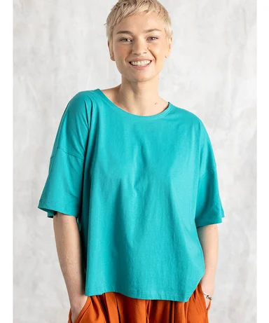 A woman wearing a blue, short-sleeve top from Gudrun Sjödén.