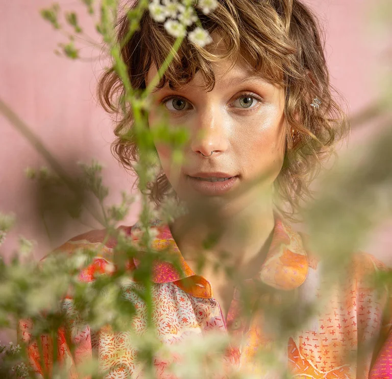 A woman’s face behind green stems.