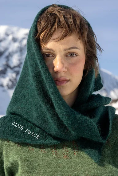 A woman with a green, knitted shawl from Gudrun Sjödén’s 2025 Christmas collection draped over her head.