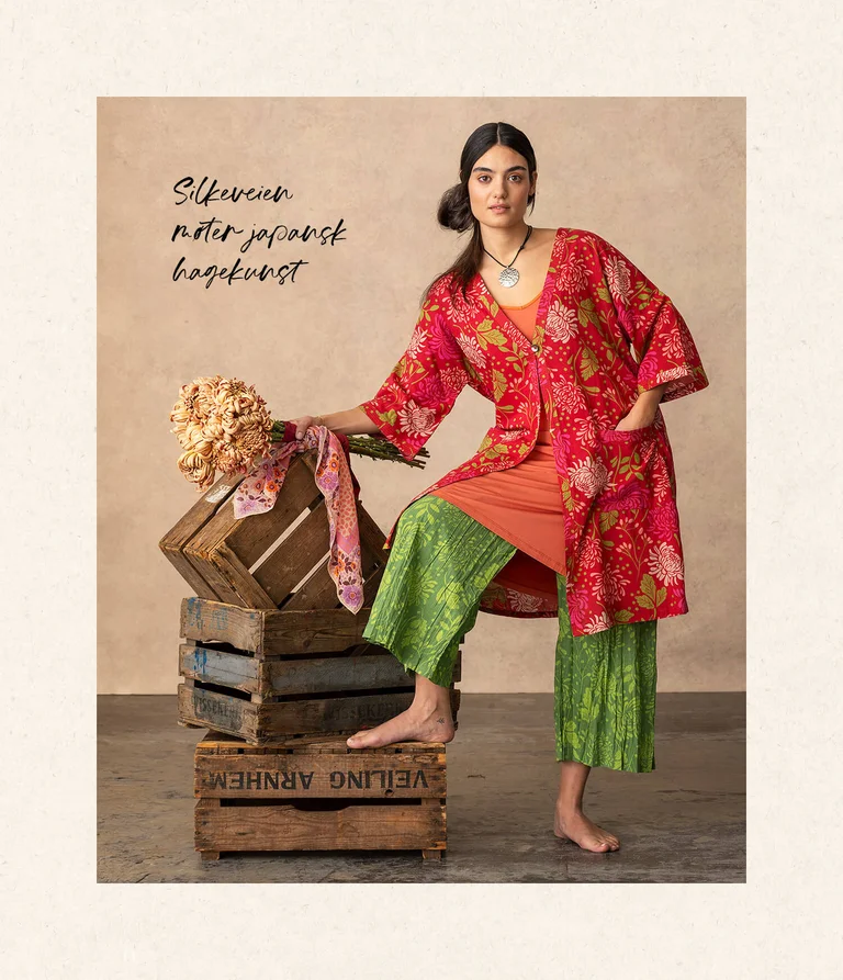 A woman wearing green pants and a red cardigan from Gudrun Sjödén. 