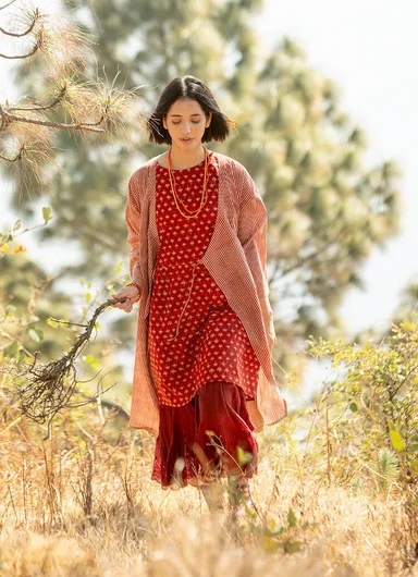 A woman walking outdoors wearing layers of clothes from Gudrun Sjödén.