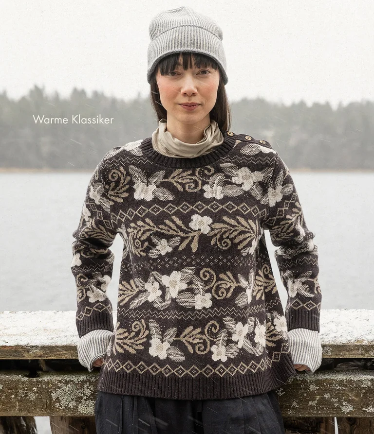 Eine Frau in einem geblümten Strickpullover von Gudrun Sjödén. 