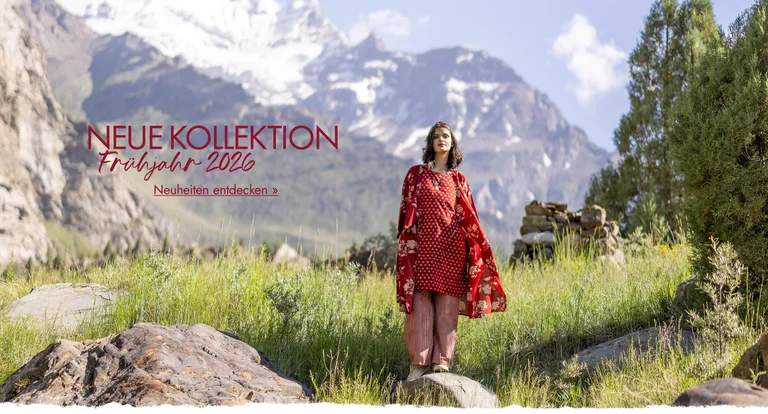 Eine Frau steht in einer Berglandschaft. Sie trägt Lagenlook aus roter Webware von Gudrun Sjödén.