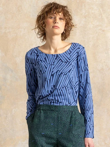 A woman wearing a patterned blue jersey top from Gudrun Sjödén.
