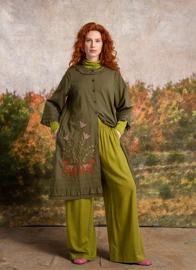 A woman wearing layers of clothes in shades of green from Gudrun Sjödén.