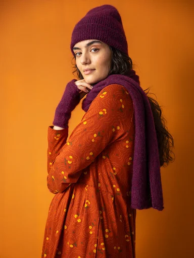 A woman wearing a knitted beanie, scarf and fingerless gloves from Gudrun Sjödén.