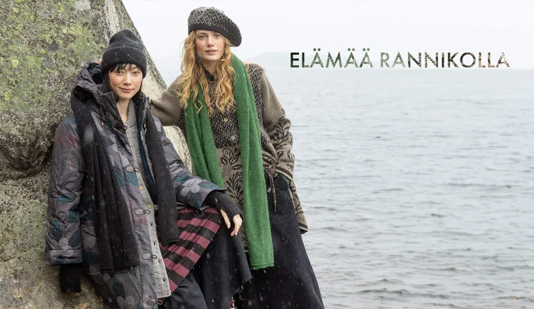 Two women wearing layers of clothing and accessories from Gudrun Sjödén’s 2025 winter collection. 