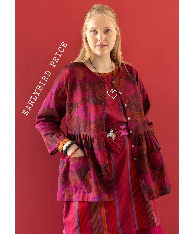 A woman wearing a button-up pink-red blouse from Gudrun Sjödén’s 2025 Christmas collection.