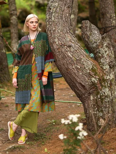 A woman wearing layers of colorful clothing from Gudrun Sjödén.
