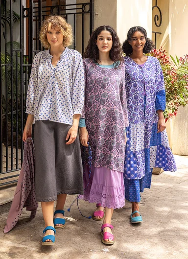 Three women next to each other wearing purple and blue patterned clothes from Gudrun Sjödén.