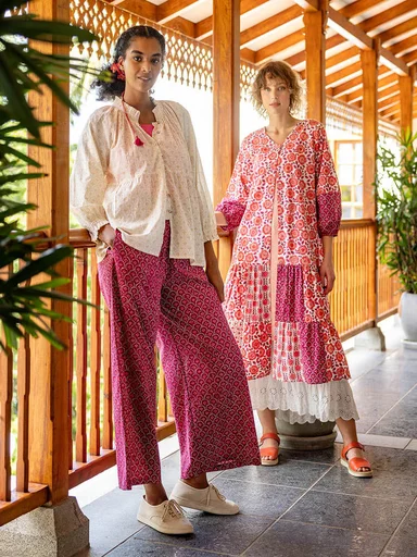Two women on a porch wearing white and pink clothes from Gudrun Sjödén.
