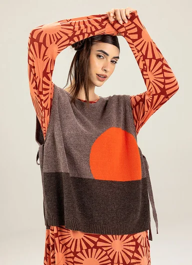 A woman wearing a knitted waistcoat over a patterned dress from Gudrun Sjödén.