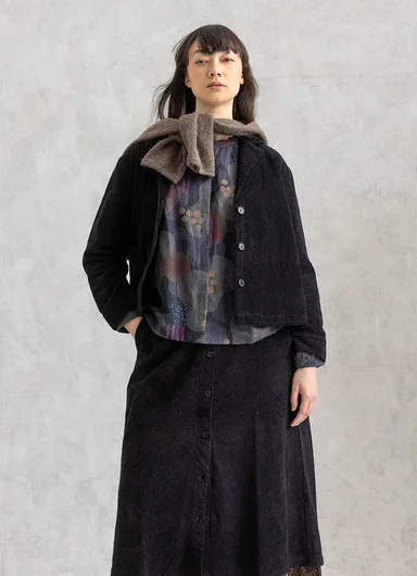 A seated woman wearing turquoise corduroy clothes from Gudrun Sjödén.