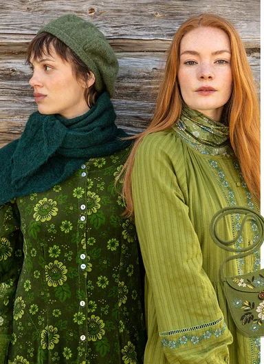 Two women standing close together wearing clothes in green tones from Gudrun Sjödén’s 2025 Christmas collection.