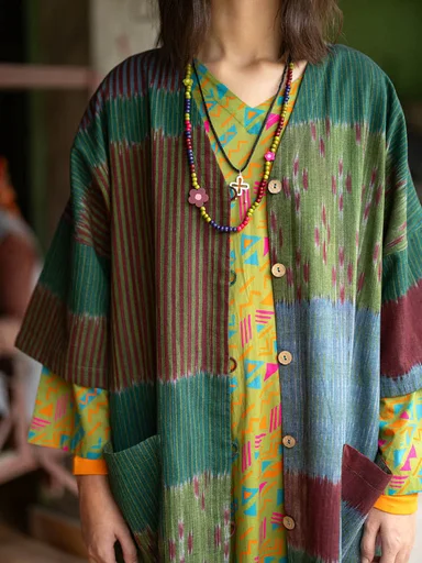 An upper body wearing layers of patterned clothes from Gudrun Sjödén.