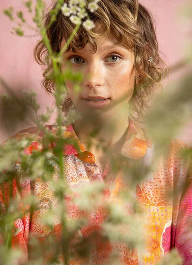 An upper body wearing layers of patterned clothes from Gudrun Sjödén.