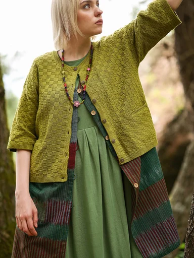A woman wearing layers of green clothes from Gudrun Sjödén.