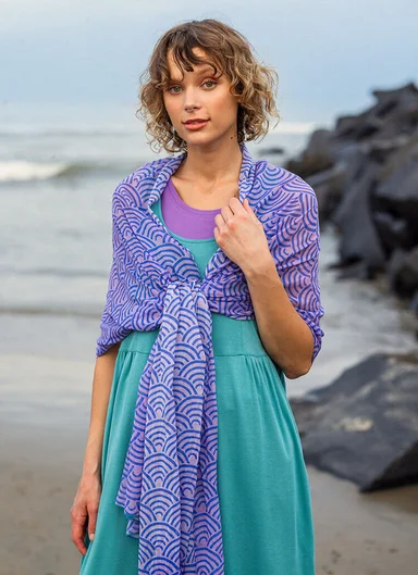 A woman on a beach with a purple shawl from Gudrun Sjödén around her shoulders.