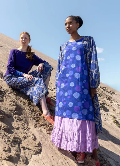 A woman sitting down wearing colourful clothes from Gudrun Sjödén.