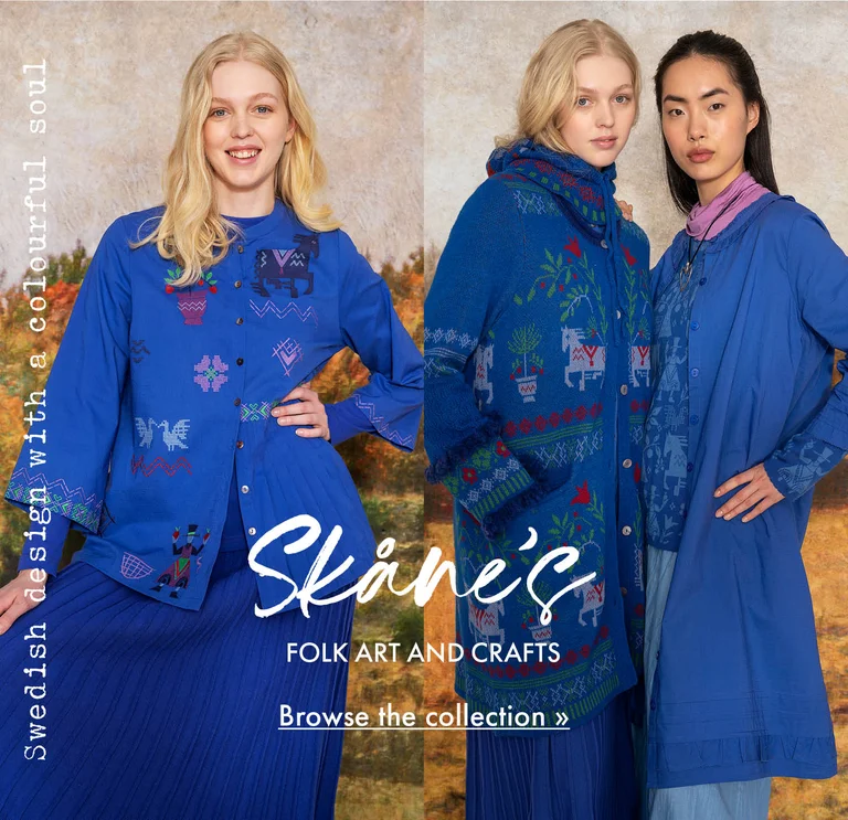 A collage with three photos of: two women wearing folk-art patterned clothes, a close-up of a woman wearing a blue knitted balaclava with a floral pattern, and a woman wearing a blue embroidered blouse and blue skirt from Gudrun Sjödén. A painted autumnal landscape is visible in the background.