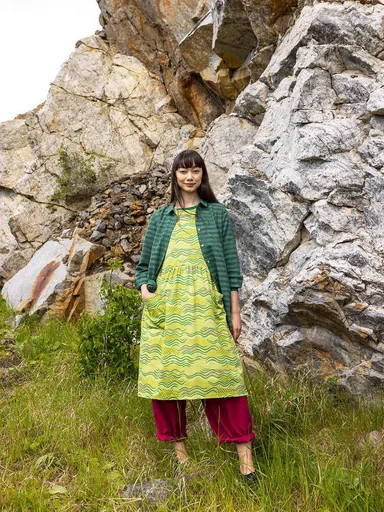 A woman in front of a rock face wearing layers of clothes from Gudrun Sjödén.