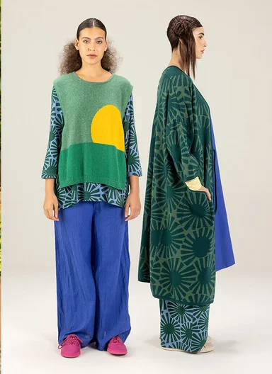 A woman wearing a knitted waistcoat over a patterned dress from Gudrun Sjödén.