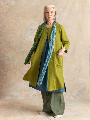 A woman in a studio wearing layers of woven clothes from Gudrun Sjödén.