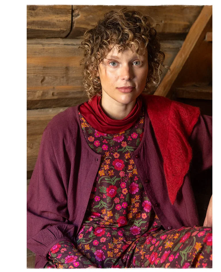 A woman wearing layers of reddish-pink clothes from Gudrun Sjödén.