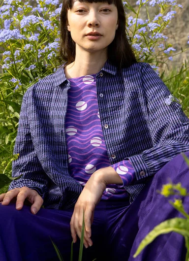 A woman in front of a rock face wearing layers of clothes from Gudrun Sjödén.