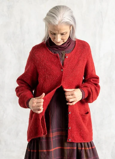 Three women wearing red and burgundy clothes from Gudrun Sjödén’s Essentials collection, photographed in a studio setting.