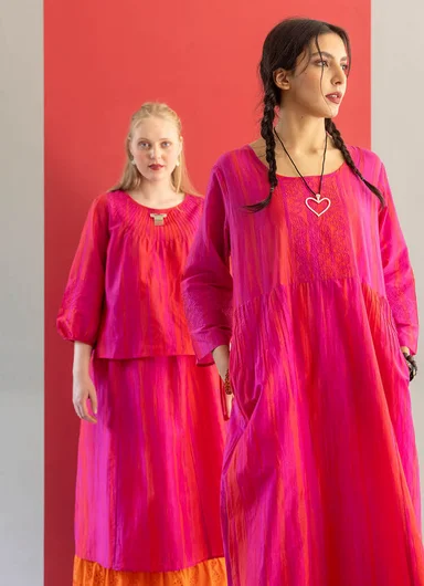 Two women wearing lustrous, pink pieces from Gudrun Sjödén’s Festive Shimmer collection.