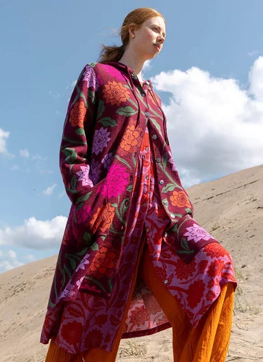 A woman sitting down wearing colourful clothes from Gudrun Sjödén.